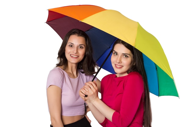 Deux jeunes femmes souriantes avec parapluie arc-en-ciel.