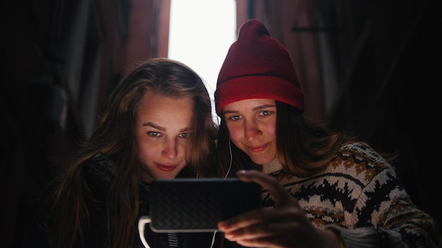 Deux jeunes femmes souriantes regardant l'écran du téléphone avec des écouteurs