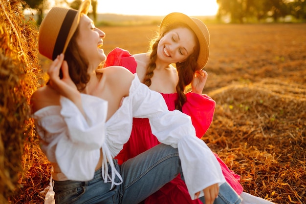 Deux jeunes femmes souriantes se reposant près d'une botte de foin Concept de mode Vacances dans la nature Relaxation et style de vie