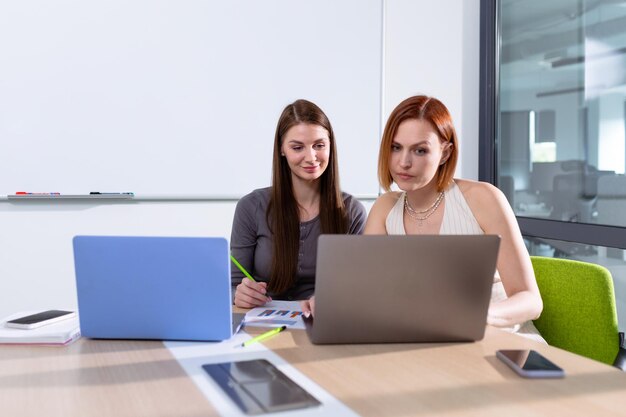 Deux jeunes femmes travaillent sur un projet dans une salle de réunion