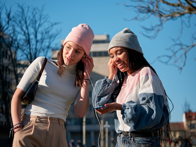 Deux Jeunes Filles, Amis, écoutant De La Musique à Travers Les écouteurs D'un Smartphone