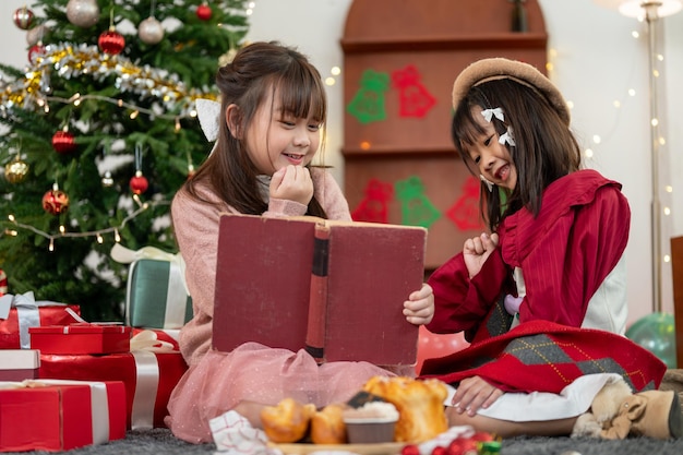 Deux jeunes filles asiatiques joyeuses aiment lire ensemble un conte de fées de Noël dans un livre