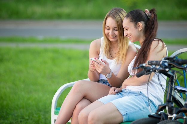 Deux jeunes filles dans un banc regardant leur téléphone