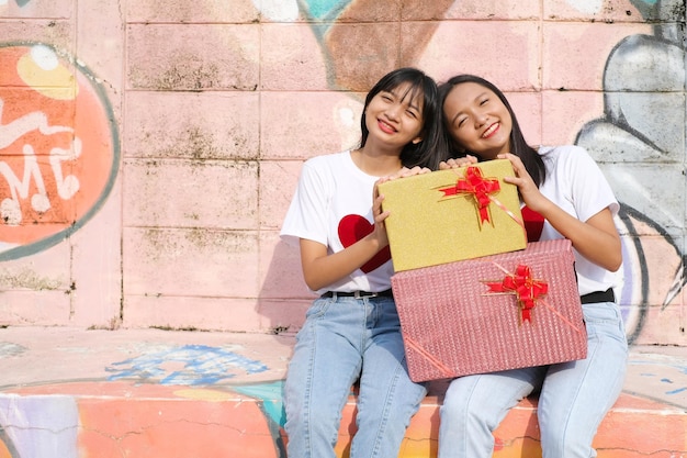 Deux jeunes filles heureuses avec boîte-cadeau sur fond coloré