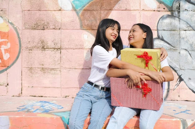 Deux jeunes filles heureuses avec boîte-cadeau sur fond coloré