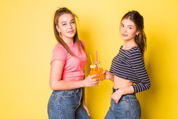 Deux jeunes filles joyeuses de beauté naturelle hipster posant ensemble sur fond jaune