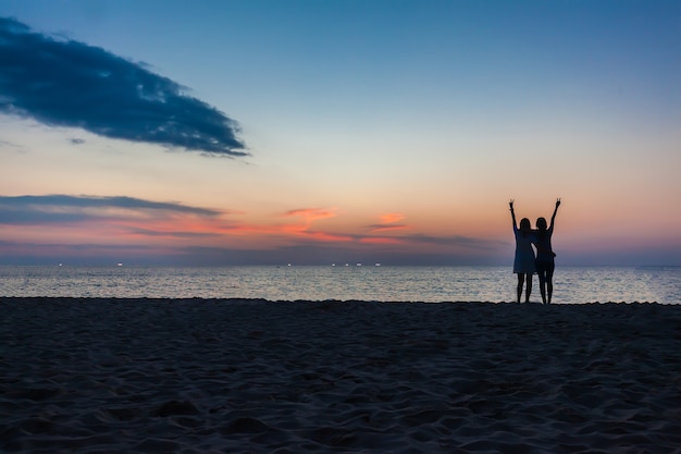 Deux jeunes filles s'amusant sur la plage avec un coucher de soleil