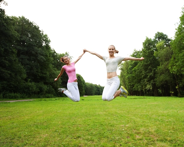 Deux jeunes filles sautent dans le parc d'été