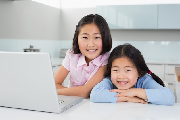 Deux jeunes filles souriantes avec ordinateur portable dans la cuisine