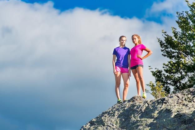 Deux jeunes filles sportives debout au sommet de la montagne - triomphe