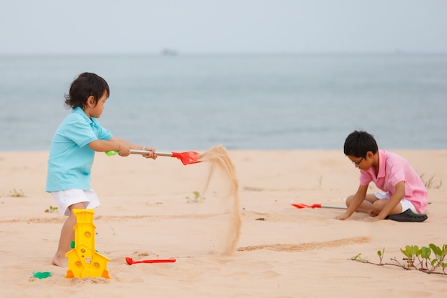 Deux jeunes frères jouant sur la plage de sable