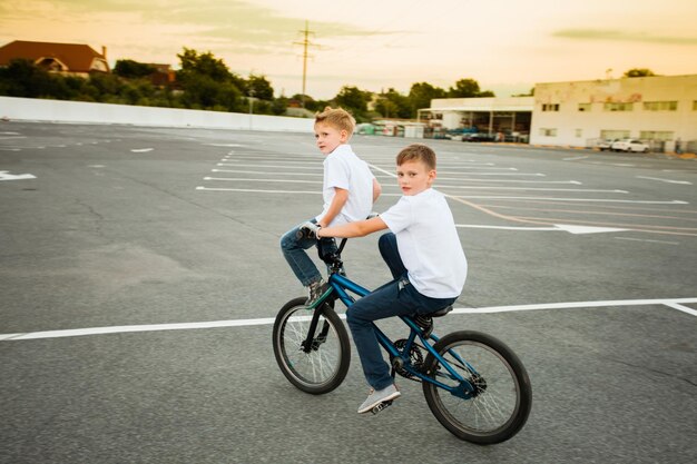 Deux jeunes frères en t-shirts blancs, montrant leurs compétences amusantes à vélo, regardant la caméra. Concept de mode de vie actif