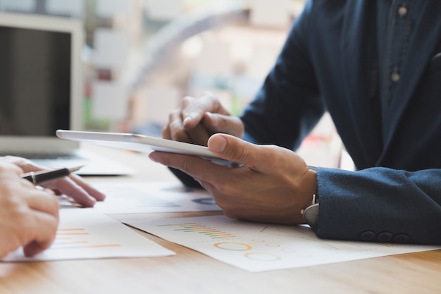 Deux jeunes hommes d'affaires à l'aide du pavé tactile et de l'analyse du document graphique de l'entreprise