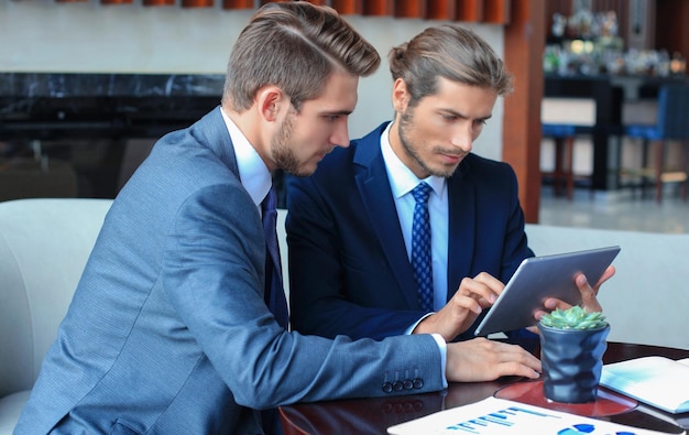 Deux jeunes hommes d&#39;affaires qui utilisent le pavé tactile lors de la réunion