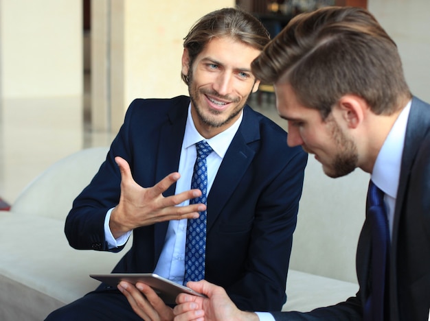 Deux jeunes hommes d'affaires utilisant le pavé tactile lors d'une réunion.