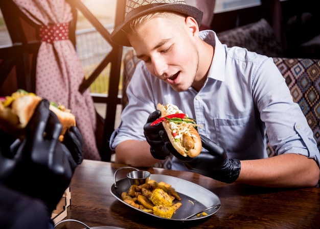 Deux Jeunes Hommes Affamés Mangeant Un Hot-dogs Au Café. Restaurant