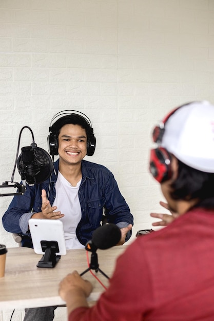 Photo deux jeunes hommes au style décontracté s'interviewent pour un podcast radio.