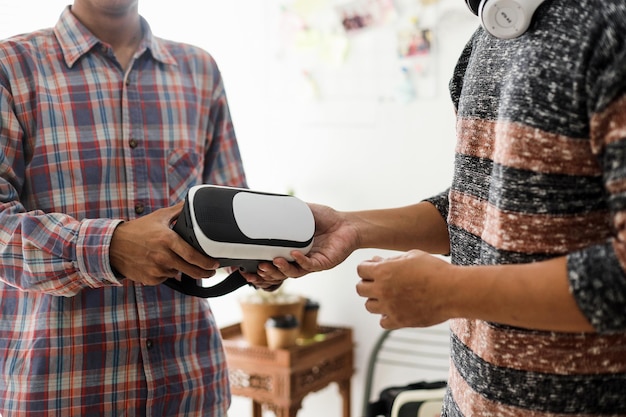 deux jeunes hommes au style décontracté tenant des lunettes VR. Copiez l'espace et faites une maquette pour l'appareil technologique.