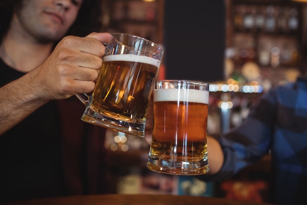 Deux jeunes hommes grillant leurs chopes à bière