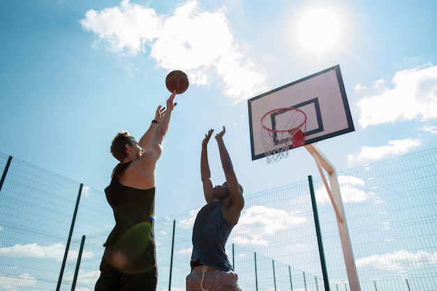 Deux jeunes hommes jouant au basket-ball à l'extérieur