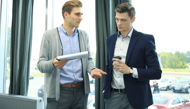 Deux jeunes hommes modernes discutant du travail au bureau.