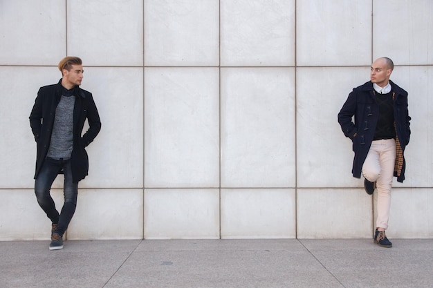 Deux jeunes hommes modernes sur un mur blanc