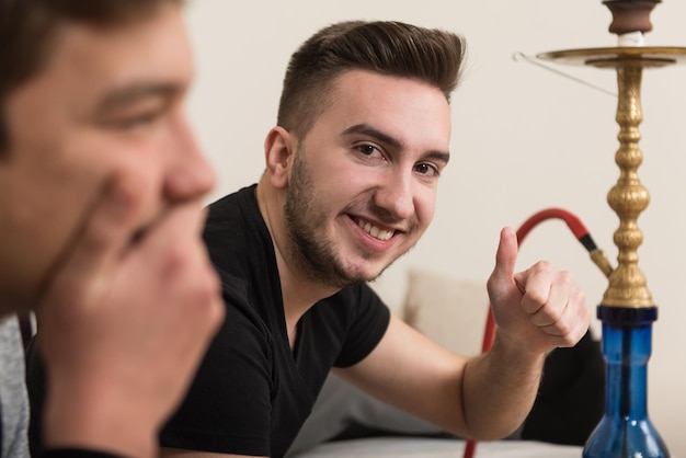 Deux jeunes joueurs assis ensemble sur un canapé et jouant à des jeux vidéo à la maison