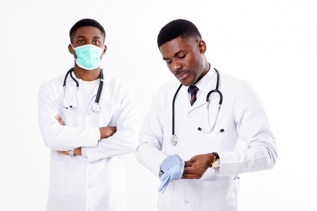 Deux jeunes médecins africains sur un blanc isolé avec un phonendoscope. L'un d'eux avec un masque.