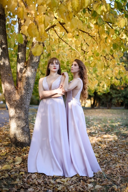 Deux jeunes princesse vêtue d'une jolie robe beige dans un parc en automne. Photo de mode.