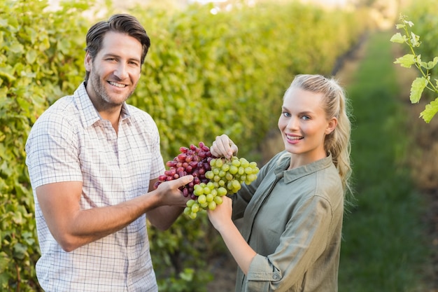 Deux jeunes vignerons heureux tenant des raisins