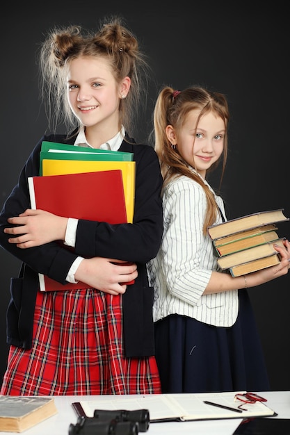 Deux jolies écolières brune tenant le livre isolé sur fond noir