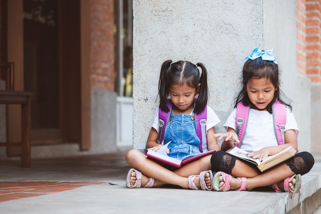 Deux Jolies Filles Asiatiques Lisant Un Livre Ensemble à L'école Avec Plaisir Et Bonheur