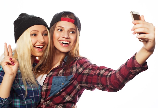 Photo deux jolies filles hipster qui prennent un selfie isolées sur un fond blanc