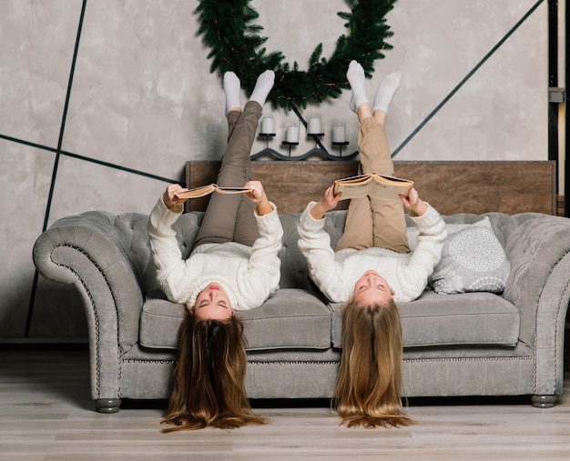 Deux jolies filles posant avec l'expression du visage qui s'embrasse à la fête d'anniversaire. Dame européenne aux cheveux longs debout à côté de l'arbre et des cadeaux