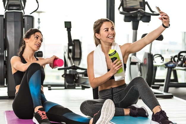 Deux jolies filles prenant une photo de selfie tout en s'entraînant au gymnase