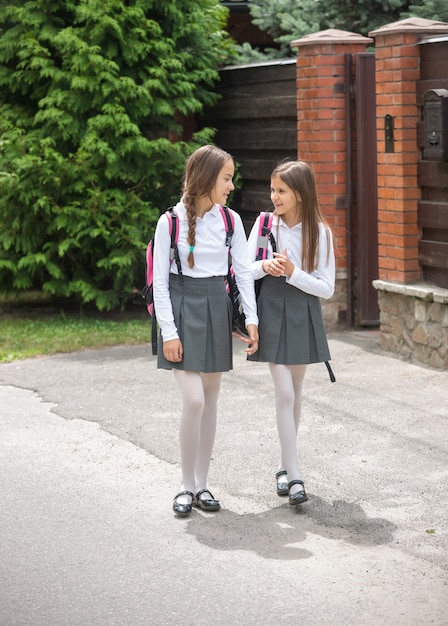 Deux jolies filles en uniforme marchant jusqu'à l'école et discutant
