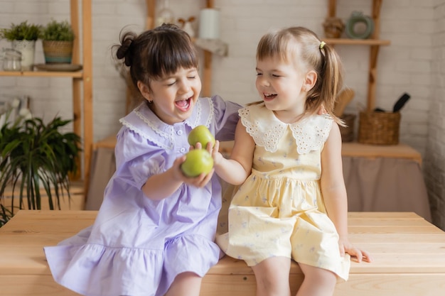 deux jolies petites filles drôles en robes mangeant des pommes vertes dans la cuisine. espace pour le texte, bannière