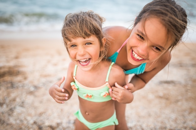 Deux jolies petites sœurs positives ont levé la main en nageant en mer pendant les vacances par une chaude journée d'été. Concept d'enfants en bonne santé et joyeux