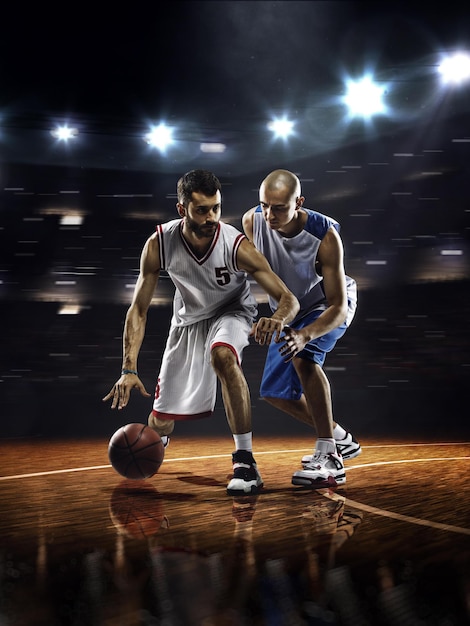 Photo deux joueurs de basket-ball en action dans une salle de sport éclairée