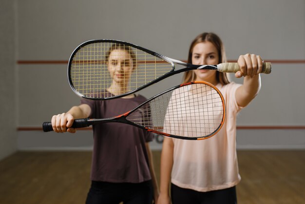 Deux joueuses montrent des raquettes de squash. Filles en formation, passe-temps sportif actif, entraînement de fitness pour un mode de vie sain