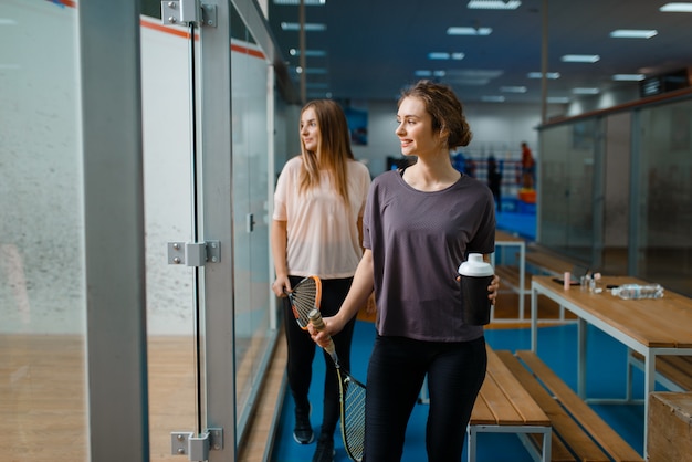 Deux joueuses de squash souriantes dans une salle de sport. Jeunes à l'entraînement, passe-temps sportif actif, entraînement de remise en forme pour un mode de vie sain