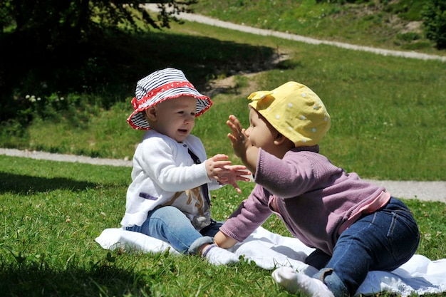 Deux joyeuses petites filles caucasiennes jouant ensemble sur l'herbe dans le parc Concept de maternité enfance amitié et vacances d'été