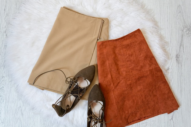 Deux jupes en daim marron et des chaussures en fourrure blanche.