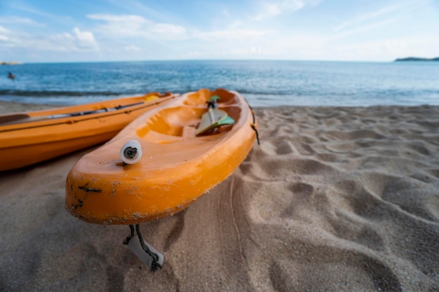 Deux kayaks orange colorés sur une plage de sable prêts pour les pagayeurs en journée ensoleillée