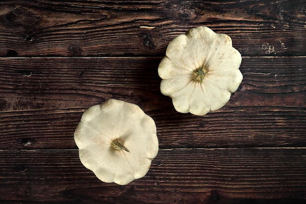 Deux légumes de courge pattypan sur une planche en bois sombre, vue d'en haut.