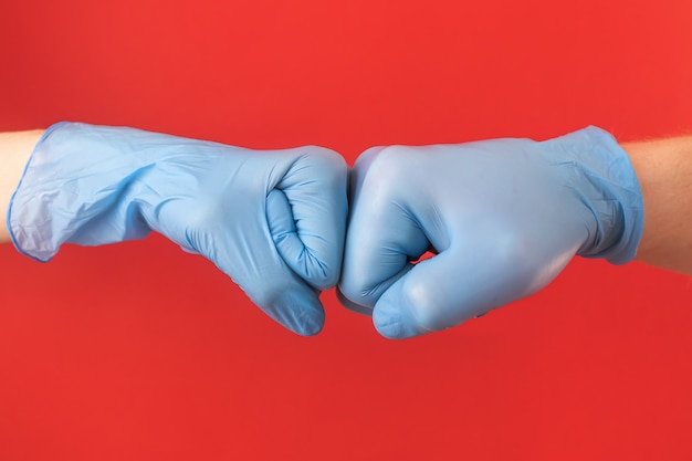 Photo deux mains dans des gants médicaux bleus tiennent leurs poings, comme une salutation. concept de protection contre un virus, pandémie, épidémie, maladie. minimalisme, copyspace. main masculine et féminine.