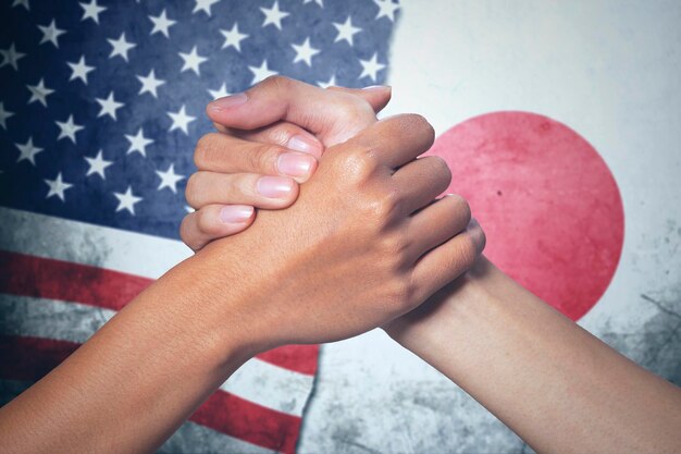 Photo deux mains avec le drapeau du japon et des états-unis