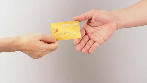 Deux mains envoient et reçoivent une carte de crédit en or sur fond blancx9