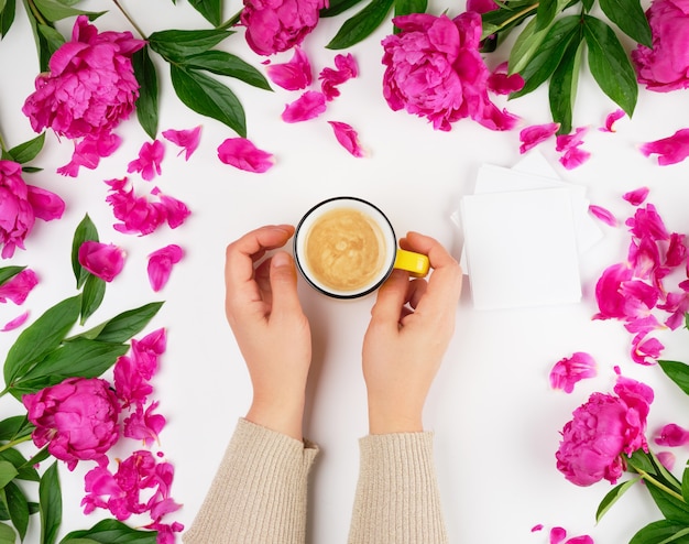 Deux mains féminines tenant une tasse en céramique jaune avec café noir