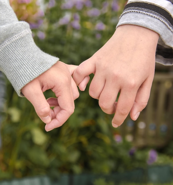 Les deux mains des filles des copines sont des doigts entrelacés